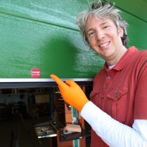 Man pointing at Garage Door Systems logo on a garage door
